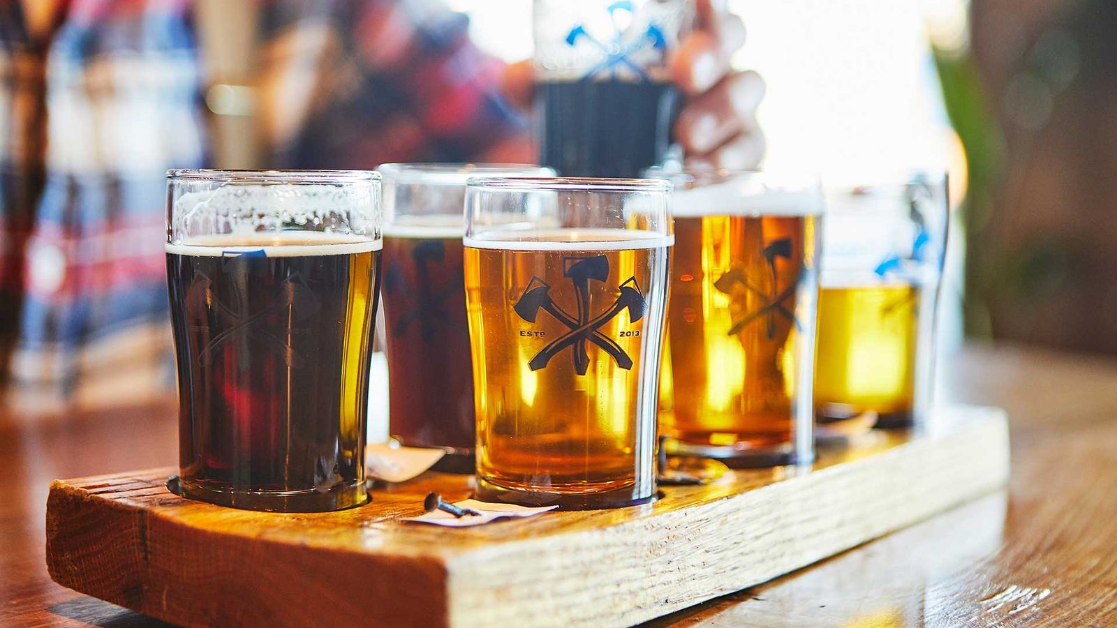 A flight of four beers, light to dark, on a wooden paddle